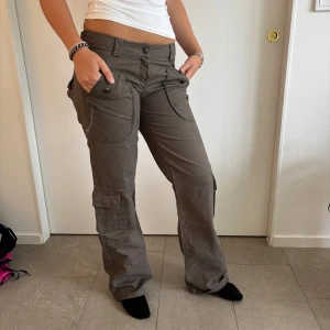 Coola gröna cargopants med fickor - Säljer ett par gröna cargopants med flera stora fickor och coola detaljer. Byxorna har låg midja och raka ben med lite loose . Materialet känns slitstarkt och passar till många outfits. Gylfen är tyvärr trasig så är villig att diskutera priset