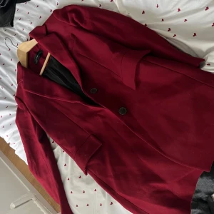 Vinröd kavaj från zara - Stilren vinröd kavaj från zara med klassisk krage och två knappar framtill. Jackan har långa ärmar och två fickor med lock. Perfekt för dig som vill ha en snygg och tidlös look.