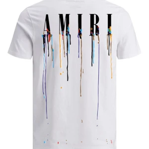 Vit AMIRI t-shirt med färgstänk - Vit t-shirt från AMIRI med tryck av loggan och färgstänk i flera nyanser på både fram- och baksida. Klassisk passform med rund hals och korta ärmar. Snygg streetstyle-vibe och tillverkad i mjuk bomull.