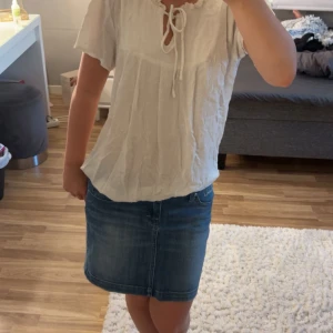 Vit blus med knyt från JDY - Supersöt vit blus från JDY i storlek 34. Blusen har korta ärmar, knytning vid halsen och små volangdetaljer upptill. Tunt, luftigt tyg med diskret struktur och prickar i materialet. Tröjan är skrynklig på bilden men det är ju bara att styrka💕passar mig som använder 36 i vanliga fall!