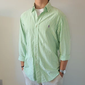 Randig Ralph Lauren Skjorta - Stl M, Custom Fit - Hej säljer en fin Ralph Lauren skjorta I randigt mönster med färgerna grön och vit, Perfekt till sommaren! 🏖🏝 | Skick: 8,5/10 | Stl: M, Slim fit | Han på bilden är 172cm | Fraktar spårbart med Instabox eller Postnord | Mvh Galgen 🤗