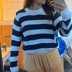 Randig stickad tröja i blått och vitt - Säljer en ribbstickad tröja med breda marinblå och vita ränder. Tröjan har rund halsringning och långa ärmar. 