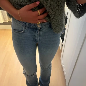 Blå raka jeans med hål på knät - Säljer ett par klassiska blå jeans med raka ben och snyggt hål på ena knät. Jeansen har hög midja och är i ett mjukt denimtyg som sitter skönt. Perfekta för en chill och trendig look.