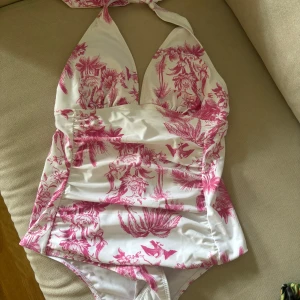 Oanvänd baddräkt – storlek M  - Säljer denna superfina baddräkt i vitt med rosa, botaniskt mönster. Halterneck med knyt i nacken – sitter snyggt och ger superfin passform.  Oanvänd.  Nypris ca 500 kr – mitt pris: 100kr då jag flyttrensar.    Skicka PM vid intresse! 