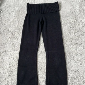 Svarta stickade byxor Gina Tricot - Svarta stickade byxor från Gina Tricot med bred ribbad midja. Byxorna har en rak passform och är perfekta för en chill och avslappnad stil. Mjukt material som känns skönt mot huden.