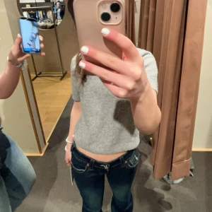 Grå stickad kortärmad tröja från Zara  - Supermysig grå stickad tröja med korta ärmar och rund hals. Perfekt till jeans eller kjol för en chill och stilren look. Tröjan har en enkel design och är lite croppad, vilket ger en modern vibe.