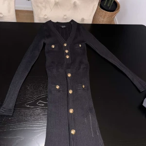 Svart ribbad långklänning - Supersnygg svart långklänning med guldknappar, sitter jättefint och aldrig använd. 