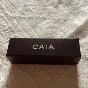 CAIA Hazelnut Contour Stick - Säljer en CAIA Hazelnut Contour Stick, en krämig konturstick i en kall hasselnötsnyans. Perfekt för att skapa skuggor och framhäva ansiktsdragen. Kommer i en stilren svart förpackning med silvrig logga. Enkel att blenda för ett naturligt resultat.