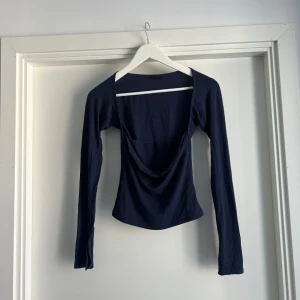 Mörkblå långärmad topp Gina Tricot - Mörkblå långärmad topp från Gina Tricot med snygg draperad urringning framtill. Figurnära passform och tillverkad i mjuk bomullsmix. Perfekt för dig som gillar stilrena och trendiga plagg med en twist.