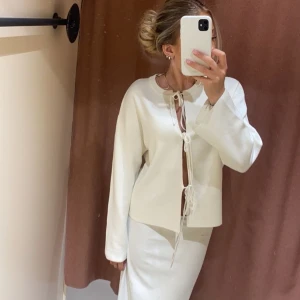 Vit tröja med snörning - Säljer en superfin vit kofta med snörning framtill. Tröjan har vida ärmar och är gjord i ett mjukt material som känns skönt mot huden. Perfekt att styla med jeans eller kjol. Den kommer från Gina tricot och är i storlek XS. OBS: den har en liten orange fläck, men inget som syns tydligt. 