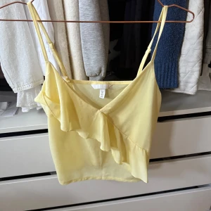 Linne med volang - Ljusgult linne med volang från H&M med smala justerbara axelband och v-ringning. 