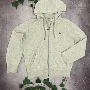Ralph Lauren zip up hoodie - Säljer denna fina och eftertraktade Ralph Lauren hoodien för bara 899kr! Nypris ligger på över 2000kr!  🎨 Färg: Grå  📏 Storlek: Medium (M) men passar S/M 📐 Mått: Fråga ifall det önskas! ♻️ Skick: 9/10 nästan som nyskick 🧵 Material: 100% bomull   ‼️Skickas dagen efter köpet genomförs‼️