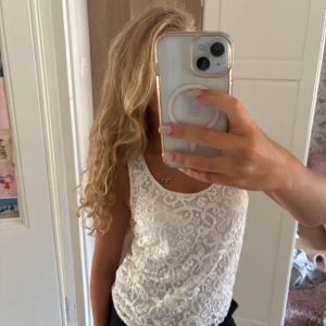 Vit spetslinne från H&M - Supersött vitt linne från H&M med spetsdetaljer och snygg dragkedja i ryggen. Linnet är ärmlöst och har en rundad halsringning. Perfekt att styla med jeans eller kjol för en fräsch look.