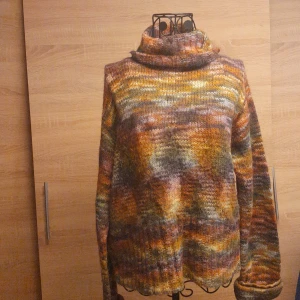 Färgglad stickad polotröja Indiska - Säljer en stickad polotröja från Indiska i storlek L. Tröjan har en mysig polokrage och ett färgstarkt mönster i orange, brunt, gult och lila. Perfekt för dig som gillar unika plagg med höstig vibe och skön passform. Långärmad och supermjuk.