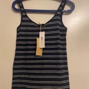 Topp - Säljer en stilren och snygg topp från Gina Tricot i mörkblått med ränder. Toppen är helt ny och aldrig använd – originalprislappen sitter kvar, dock utan pris. Passar perfekt till både vardags- och kvällsoutfits. En tidlös och mångsidig favorit i garderoben!