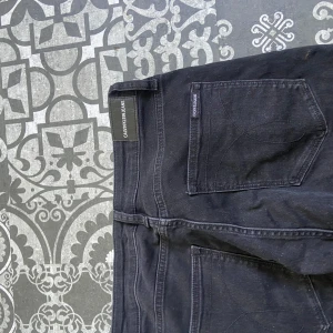 Svarta jeans från Calvin Klein Jeans - Svarta jeans från Calvin Klein Jeans med klassisk femficksdesign och diskreta logotyper på bakfickan och linningen. Jeansen har dragkedjegylf och är tillverkade i mjukt bomullsmaterial med en slim passform som sitter snyggt hela vägen ner.