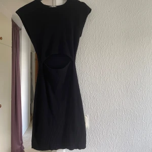 Svart ribbad cut out klänning - Snygg svart kortklänning med ribbad struktur och cut out-detalj vid midja. Klänningen är väldigt bekväm och stretchig. 