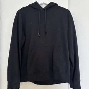 Svart hoodie från H&M XS - En klassisk svart hoodie från H&M i storlek XS. Tröjan har huva med snörning och en stor känguruficka framtill. Perfekt för en chill och avslappnad stil. Tillverkad i mjuk bomullsblandning och har långa ärmar med ribbade muddar.