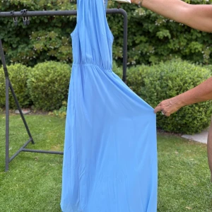 Ljusblå långklänning från Amisu - Säljer en ljusblå långklänning från Amisu med spetsdetaljer upptill och öppen rygg. Klänningen har ärmlös design och ett flowy fall. Perfekt för dig som vill sticka ut med en romantisk och somrig look eller som en balklänning.