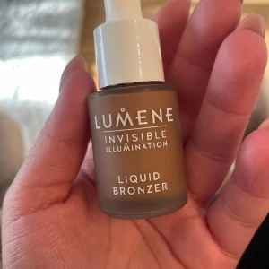 Lumene Liquid Bronzer Summer Glow - Flytande bronzer från Lumene i nyansen Summer Glow. Kommer i en smidig glasflaska med pipett för enkel applicering. Ger en naturlig solkysst look med en varm brun ton och lätt lyster. Perfekt för att framhäva ansiktets konturer och skapa glow.