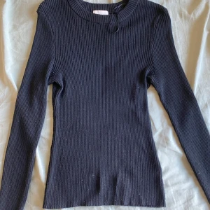 Svart ribbad långärmad tröja - En svart, ribbad långärmad tröja med rund hals från H&m i storlek S. Använd i ett få antal gånger. Tröjan har en slim passform och är tillverkad i ett stretchigt stickat material som sitter snyggt på kroppen. 