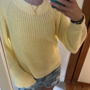 Gul stickad tröja med rund hals - Superfin ljusgul stickad tröja med rund halsringning och långa ärmar. Tröjan har en chunky ribbstickad struktur som ger en avslappnad och trendig vibe. Perfekt att slänga på sig över ett par jeans eller shorts för en fräsch look. Ljusgul!