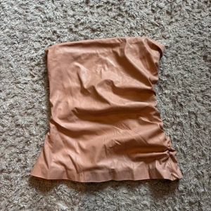 Ljusrosa tubtopp i skinn från Zara - Säljer en beige/ljusrosa tubtopp från Zara i skinn, toppen har lite skrunch på ena sidan och den är aldrig använd