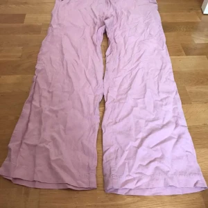 Ljusrosa vida linnebyxor 157 - Säljer ett par ljusrosa linnebyxor från 157 i storlek 160. Byxorna har elastisk midja med snörning, sidfickor och en bakficka. De är vida i modellen och har en avslappnad, loose fit. Perfekta för en chill och trendig look.