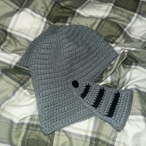 Grå stickad hjälmmössa med knappdetalj - Unik grå stickad mössa inspirerad av riddarhjälm, jättebra skick och oanvänd, endast testad bara. 
