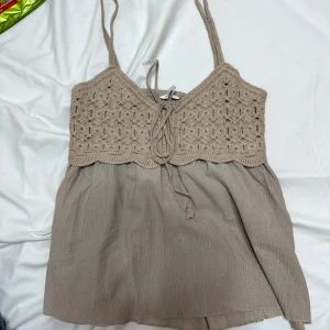 Beige virkad linnetopp med knyt - Supersöt beige linnetopp med virkad överdel och knyt framtill. Toppen har tunna axelband och en flowy nederdel i mjukt tyg. Perfekt för varma dagar och ger en bohemisk känsla. Den är köpt i Spanien för 200kr säljs då den är för liten och inte används längre, kan mötas upp i Stockholm eller fraktas men står ej för frakten, hör av er vid fler frågor!🥰