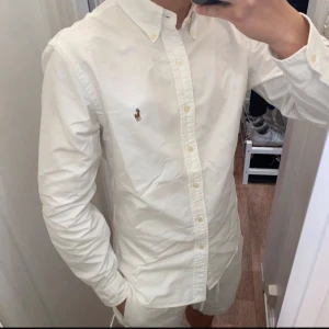 Polo Ralph Lauren (Vit skjorta) - Säljer en klassisk vit skjorta från Polo Ralph Lauren. Skjortan har långa ärmar och knappar framtill. Perfekt för en stilren look. Den är i underbar skick och redo för en ny ägare! Skjortan är size M!