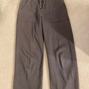 Bruna mjukisbyxor med resår och fickor - Mysiga bruna mjukisbyxor med resår i midjan och dragsko. Byxorna har två stora fickor framtill och raka ben. Perfekta för en avslappnad stil.