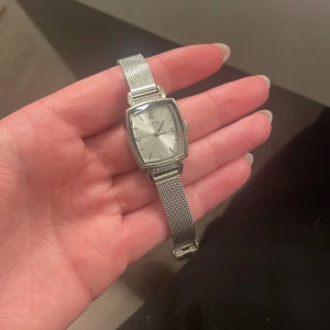 Äkta silver klocka - Stilren klocka med fyrkantig urtavla och mesharmband i silver. Urtavlan är ljus med minimalistiska markeringar och diskreta visare. Perfekt accessoar för en modern look.
