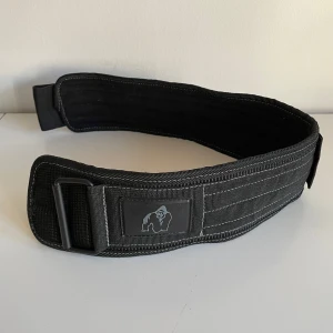 Svart träningsbälte från Gorilla Wear - Säljer ett svart träningsbälte från Gorilla Wear med kraftig konstruktion och justerbart spänne. Perfekt för styrketräning och tyngdlyftning. Bältet har tydlig logga framtill och är gjort i slitstarkt material.