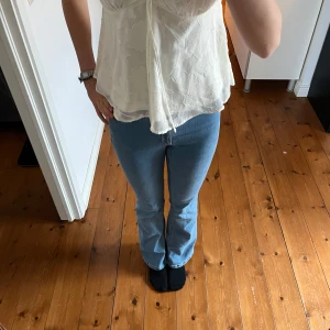 Ljusblå jeans med utsvängda ben från H&M - Säljer ett par ljusblå jeans från H&M med flared leg och medel hög midja. Jeansen har justerbar midja och klassisk femficksdesign. 