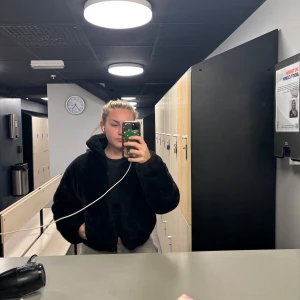 Svart pälsjacka med krage - Säljer en svart pälsjacka med hög krage och oversized passform. Jackan är mjuk och fluffig, perfekt för kyliga dagar. Stängs framtill och har en enkel, stilren design utan synliga detaljer.