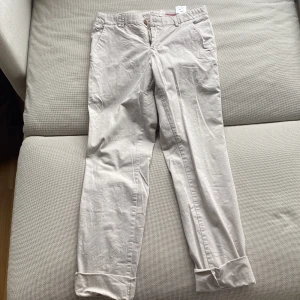 Beige chinos från H&M L.O.G.G. - Snygga beige chinos från H&M L.O.G.G. med klassisk passform och uppvikta benslut (går även att vika ner). Byxorna har fickor fram och bak samt stängs med knapp och dragkedja. Perfekta för en avslappnad men stilren look. (För små för mig)