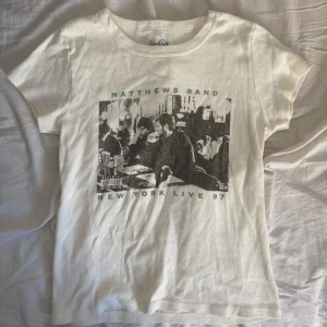 Vit topp med Matthews Band-tryck BRANDY MELVILLE - Säljer denna krämvita toppen med tryck av Matthews Band och texten 'New York Live 97' från Brandy Melville. Väldigt skön och strechtigt material☺️