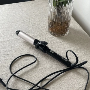 Locktång från BaByliss - Locktång med svart handtag och silverfärgad värmecylinder. Utrustad med klämma och värmeskyddande spets. Perfekt för att skapa mjuka lockar eller vågor. Sladd med roterande fäste för smidig användning. 32MM storlek 