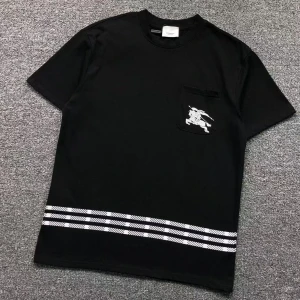 Svart t-shirt från Burberry med ficka - Säljer en svart t-shirt från Burberry med en liten ficka på bröstet som har ett vitt broderat motiv. Nertill finns vita ränder som ger en snygg kontrast. Perfekt för dig som gillar stilrena plagg med exklusiv känsla.