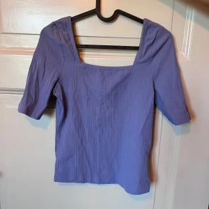 Lila ribbad topp från & Other Stories - Säljer en lila ribbad topp från & Other Stories med fyrkantig ringning och halvlånga ärmar. Toppen har en smickrande passform och är gjord i ett stretchigt material. Jättefin färg!