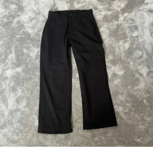 Svarta kostymbyxor från Grunt - Säljer ett par svarta kostymbyxor från Grunt med klassisk rak passform och vida ben. Byxorna har knäppning fram och är perfekta för en stilren look. Materialet känns mjukt och följsamt.