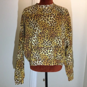Leopardmönstrad tröja från Stay - Cool långärmad tröja från Stay med leopardmönster i gula och bruna toner. Tillverkad i en mjuk blandning av ekologisk bomull och polyester. Perfekt för dig som vill sticka ut med ett djurmönster. Katter finns i hemmet!  Bara använd några gånger! 60% ekologisk bomull 40% polyester 