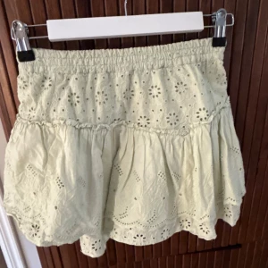 Ljusgrön broderad kjol med volang - Supersöt ljusgul kjol med broderade blommor och volangkant. Kjolen har resår i midjan. Öppen att sänka pris!!