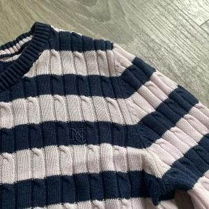 Randig stickad tröja från Gant - Säljer en ribbstickad tröja med breda marinblå och ljusrosa ränder. Perfekt för en stilren och avslappnad look. Säljer den för det är för liten