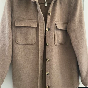 Beige vårjacka med knappar - Säljer en beige vårjacka med knappar och två bröstfickor. Märket är Object