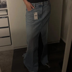 Ljusblå lång jeanskjol från Mango - Trendig ljusblå jeanskjol i lång modell med hög midja och markerad slits framtill. Säljer för att den är för lång på mig o jag är 1,67 