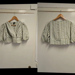 Grön- och vitrutiga blus från Vero Moda - Säljer en söt blus från Vero Moda i grönt och vitt rutigt mönster. Blusen har trekvartsärmar med resår vid ärmslut, v-ringad omlott framtill och knappar nertill. Perfekt för vår och sommar! Bara upptvättad aldrig kom till användning 