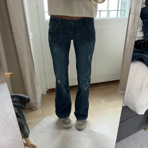 Mörkblå jeansbyxor från Bluenotes - Säljer ett par mörkblå jeansbyxor från Bluenotes med raka ben. Jeansen har lätt slitna detaljer framtill. Fint skick och sitter snyggt. Storlek 34/36. Jag är 169 cm lång, och på bilderna är mitt innerbensmått ca 82,5 cm och midjemått (platt mätt på mig) ca 31 cm.