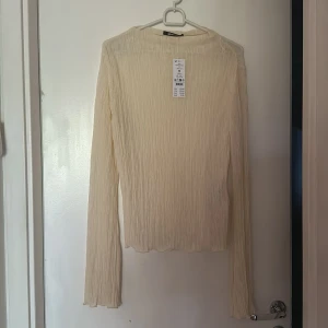 Beige ribbad långärmad topp från Gina Tricot - Säljer en beige långärmad topp från Gina Tricot. Tröjan är ribbad med en lätt transparent känsla och har en rak passform. Perfekt att styla med jeans eller kjol för en trendig look.